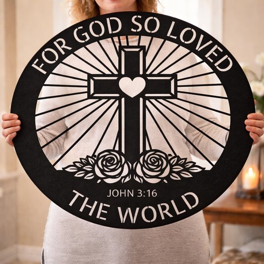 A person holds a large black circular sign featuring a cross with a heart center, sunburst rays, two roses, and the text 'FOR GOD SO LOVED THE WORLD' and 'JOHN 3:16' in a home setting.
